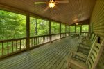 Main level screen porch with rocking chairs, bench and picnic table